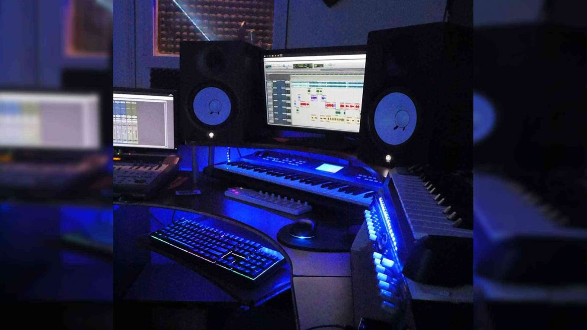 Estudio de grabación con monitores, teclado y consola iluminados en azul, donde se editan cumbias clásicas para el ambiente sonidero mexicano